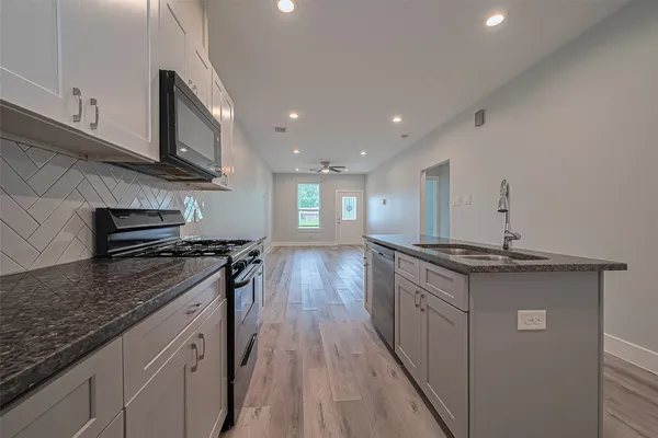 a kitchen with granite countertop a stove top oven and sink