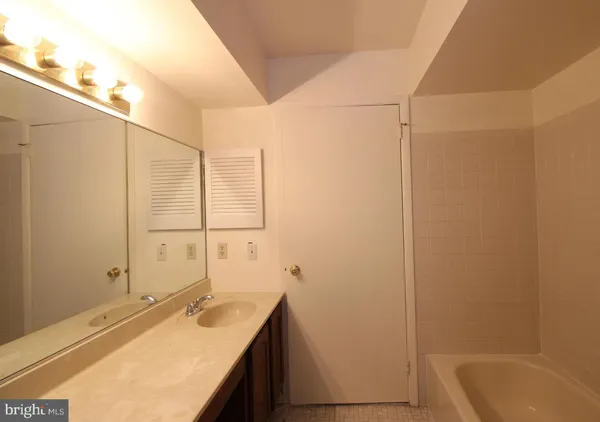 a bathroom with a granite countertop sink and a bathtub