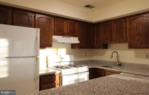 a kitchen with stainless steel appliances granite countertop a refrigerator stove a sink dishwasher and wooden cabinets