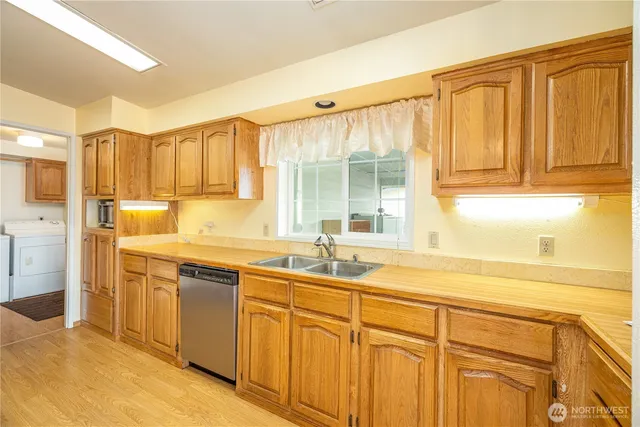 a kitchen with stainless steel appliances granite countertop a sink and cabinets with wooden floors