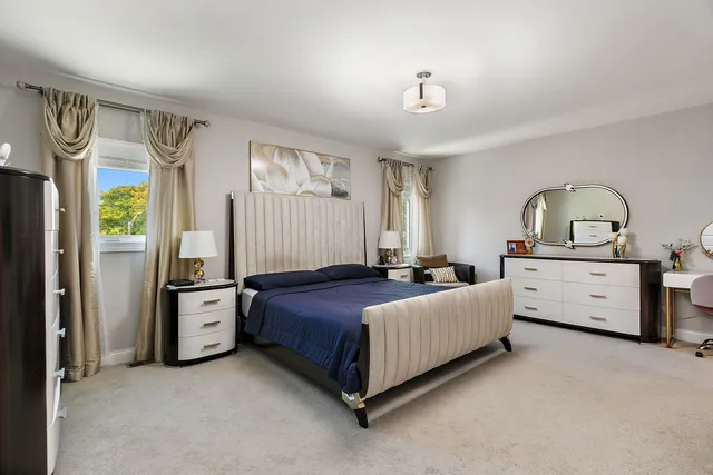 a bedroom with a bed dresser and window