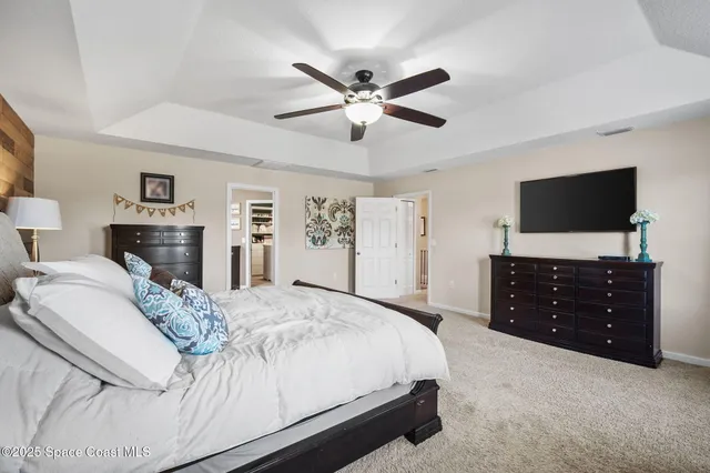 a spacious bedroom with a bed and a dresser with a flat tv screen
