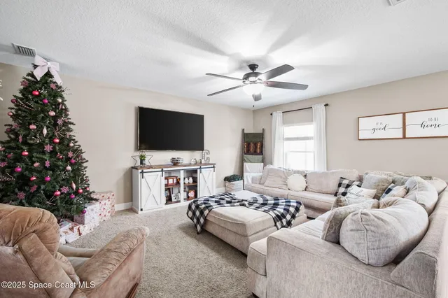a living room with furniture a flat screen tv and a christmas tree