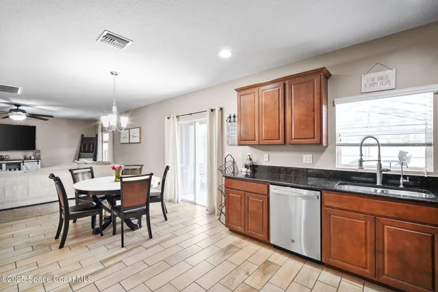 a kitchen with stainless steel appliances granite countertop a sink a stove a dining table and chairs