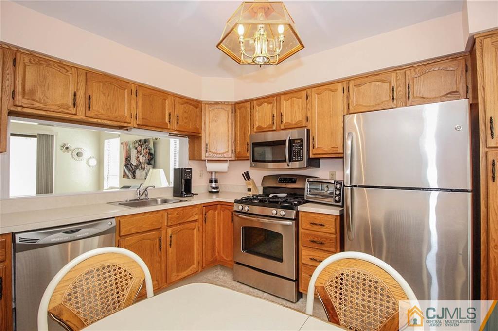 2106 Timber Oaks Road, Unit 2106 Edison, NJ 08820 - Photo 13 of 25 a kitchen with stainless steel appliances granite countertop a refrigerator a stove a sink dishwasher and wooden cabinets with wooden floor