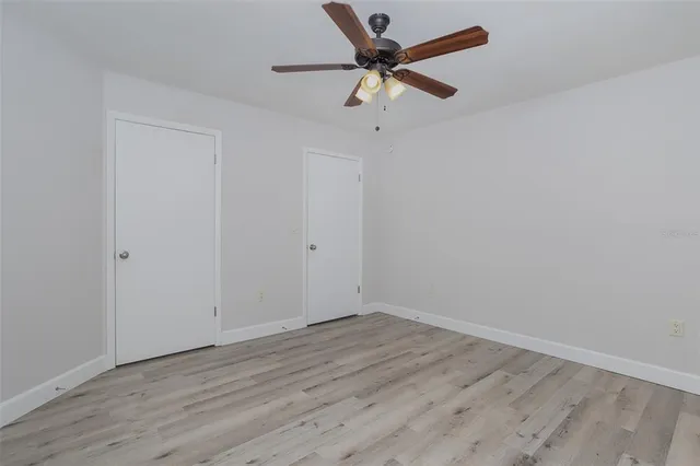 an empty room with wooden floor and a ceiling fan