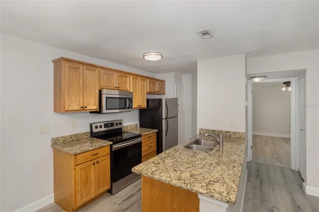 a kitchen with granite countertop stainless steel appliances a stove refrigerator and microwave
