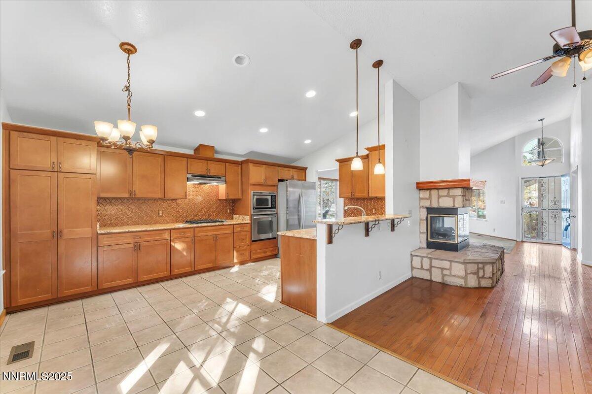 4434 Whitney Circle Sparks, NV 89436 - Photo 13 of 32 a kitchen with stainless steel appliances kitchen island granite countertop a refrigerator a oven a island and couches with wooden floor