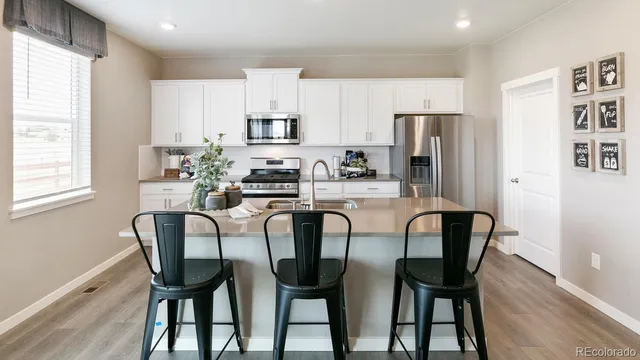 a dining room with stainless steel appliances a table chairs refrigerator and cabinets