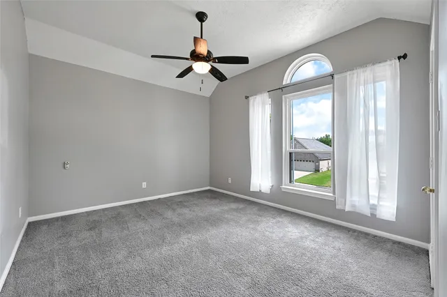 an empty room with windows and ceiling fan