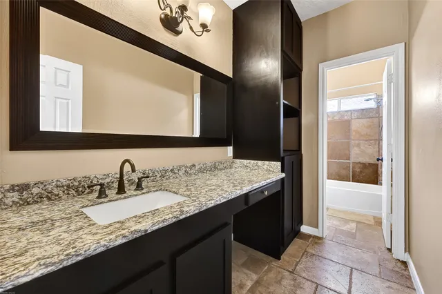 a bathroom with a granite countertop sink a mirror and a shower