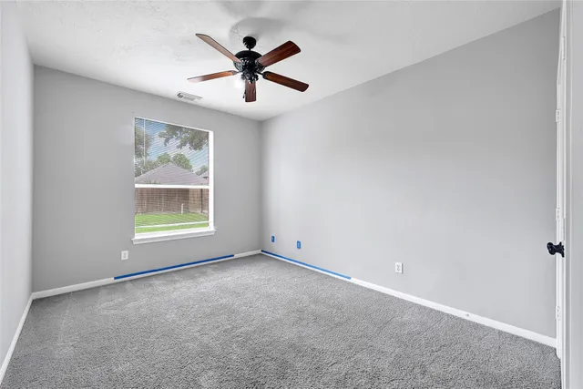an empty room with ceiling fan and windows