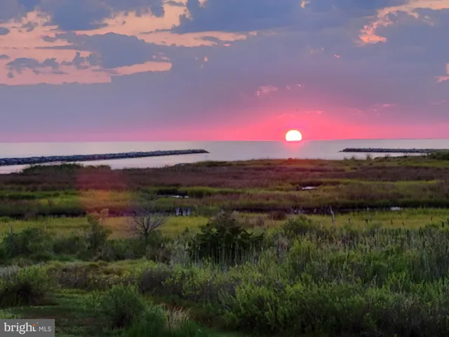 a view of a lake with sunset in background