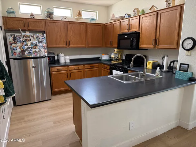 a kitchen with stainless steel appliances granite countertop a refrigerator a sink dishwasher a stove top oven a refrigerator and cabinets with wooden floor