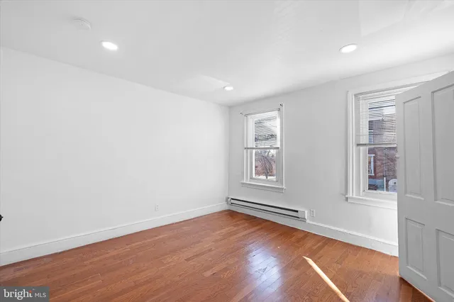 an empty room with wooden floor and windows