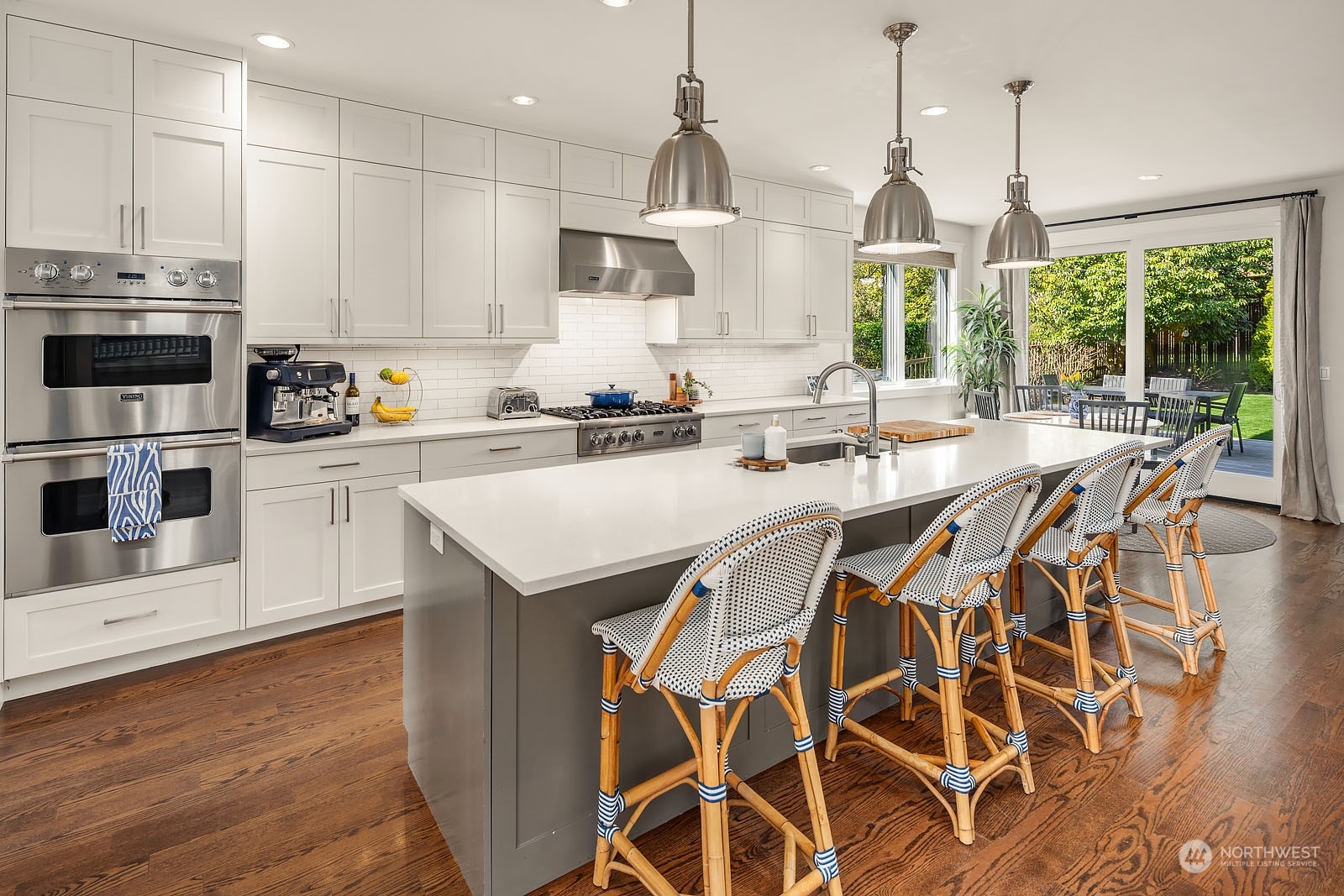 5108 Northeast 42nd Street Seattle, WA 98105 - Photo 6 of 40 a kitchen with stainless steel appliances kitchen island granite countertop a stove a sink a microwave a dining table and chairs with wooden floor