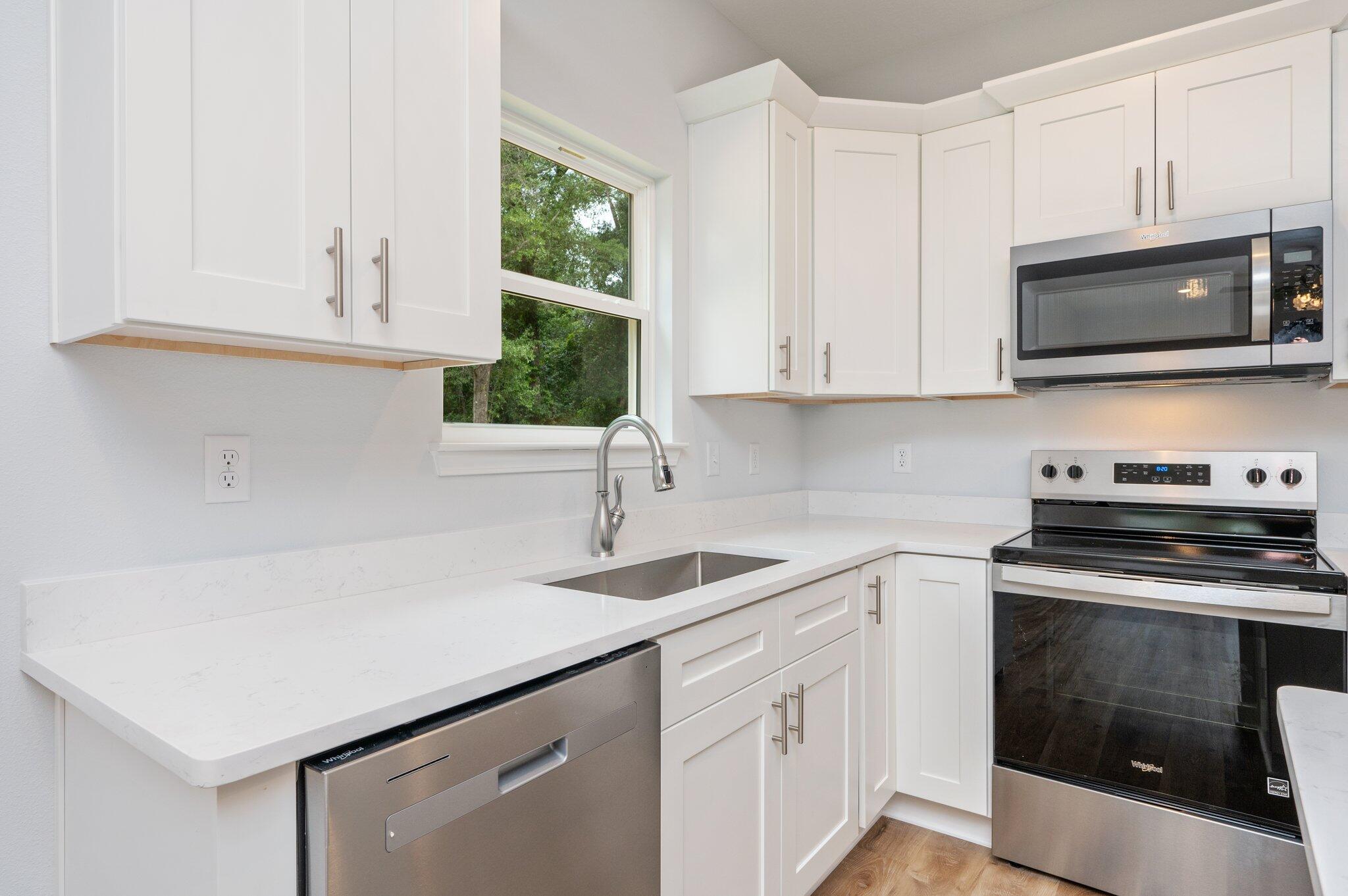 858 South Rayburn Street Crestview, FL 32539 - Photo 6 of 29 a kitchen with stainless steel appliances granite countertop a sink dishwasher a stove and a microwave oven with white cabinets
