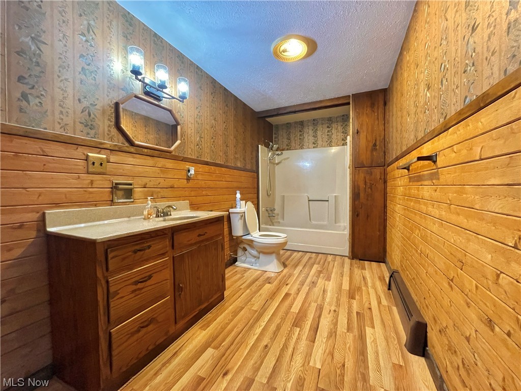 5845 Ridge Road Cortland, OH 44410 - Photo 18 of 29 Full bathroom with toilet, a textured ceiling, wooden walls, and bathing tub / shower combination