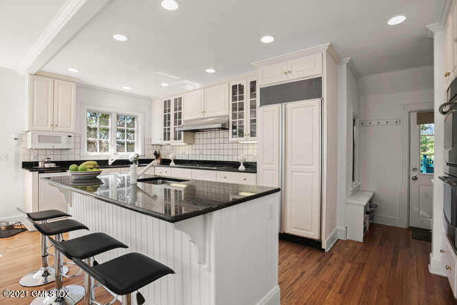 23 Parsonage Road Greenwich, CT 06830 - Photo 18 of 41 a kitchen with a sink a refrigerator a stove and white cabinets with wooden floor