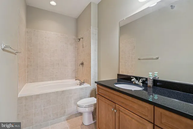 a bathroom with a granite countertop bathtub sink vanity mirror and toilet