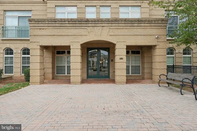 a front view of a building with a garden and trees