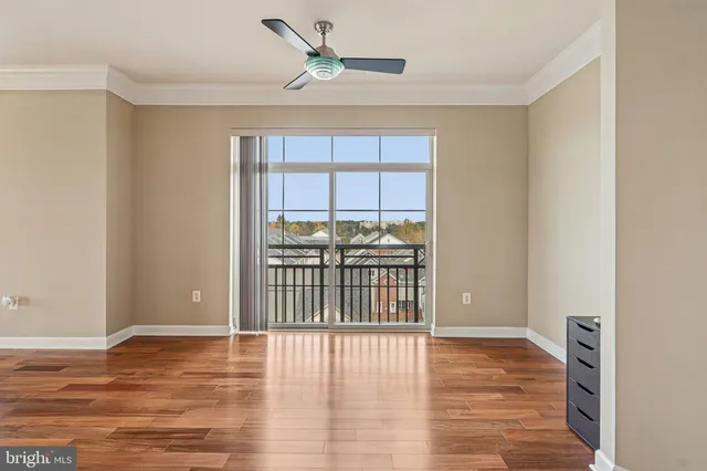 a view of a room with wooden floor and a ceiling fan