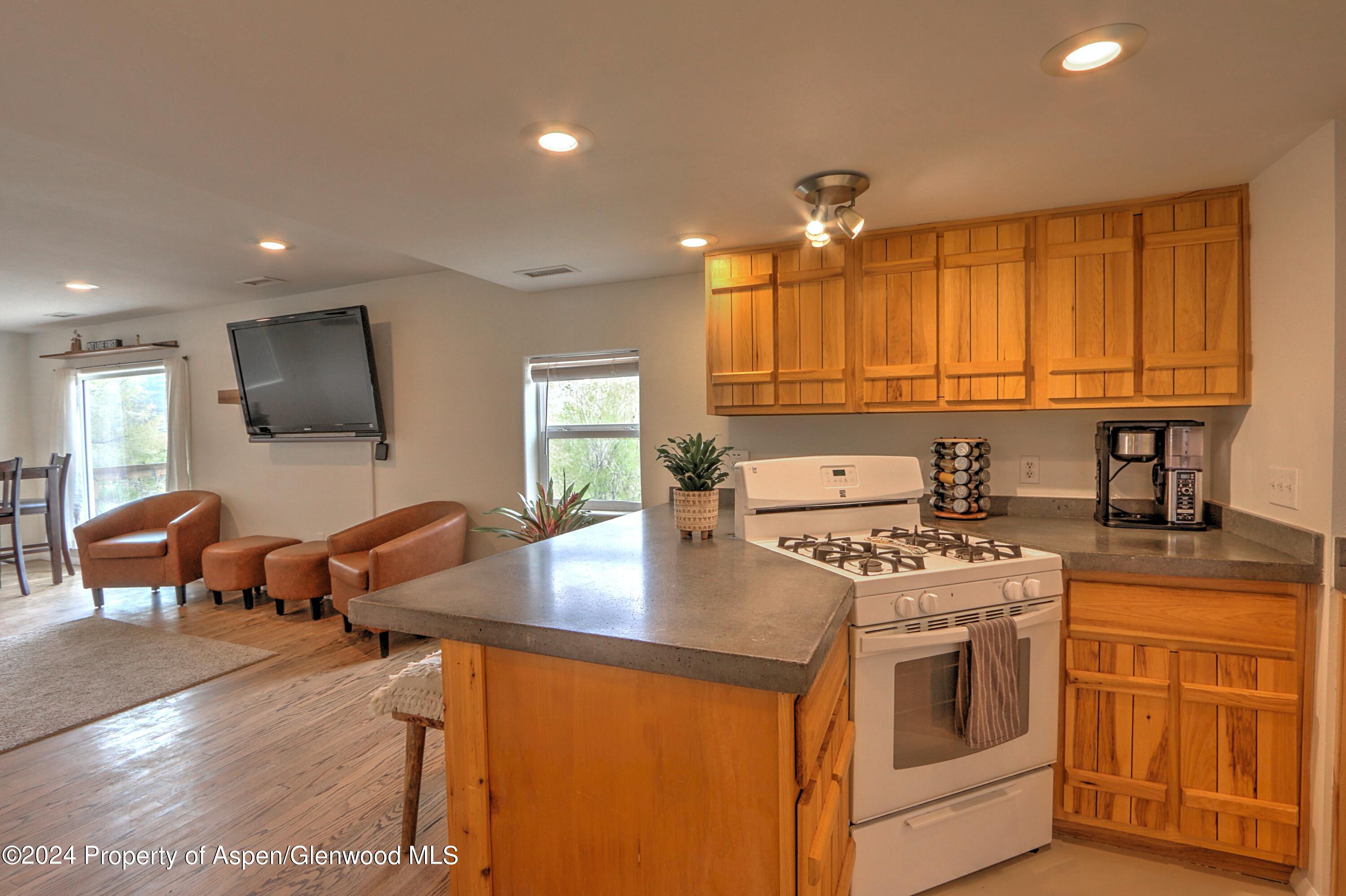 412 East 4th Street Rifle, CO 81650 - Photo 4 of 18 a kitchen with stainless steel appliances granite countertop a stove top oven a sink dishwasher and white cabinets with wooden floor