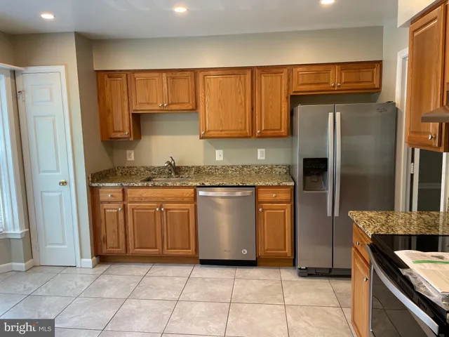 a kitchen with granite countertop a refrigerator and a stove top oven