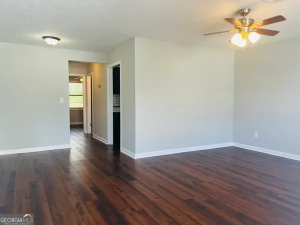 an empty room with wooden floor closet fan and windows