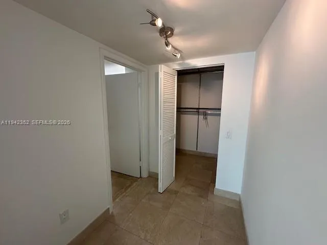a view of a room with a refrigerator and a ceiling fan