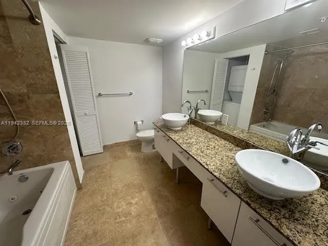 a bathroom with a granite countertop sink a toilet and a tub