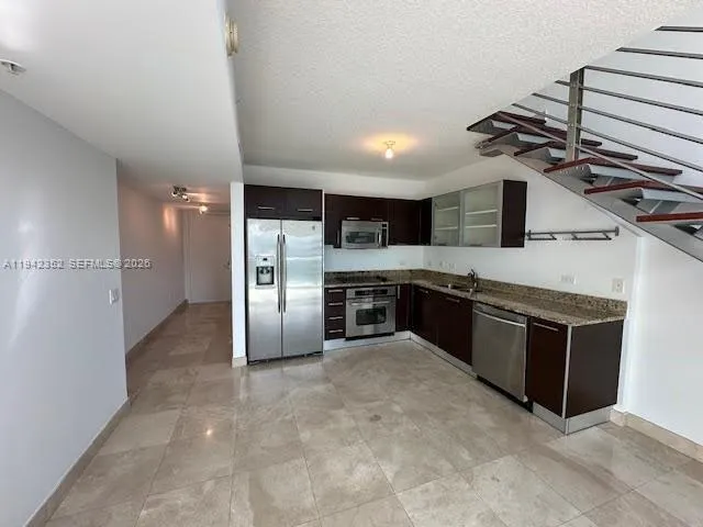 a kitchen with stainless steel appliances granite countertop a stove a sink and a refrigerator