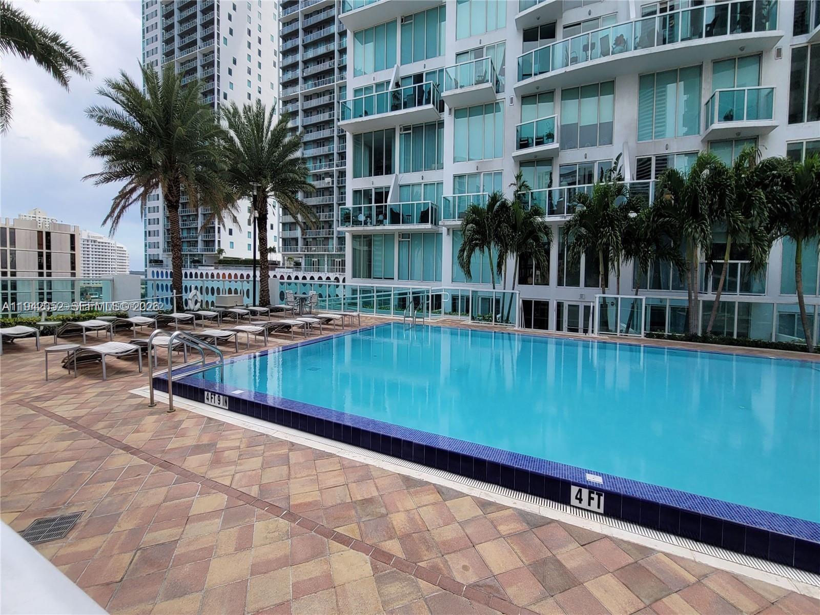 41 Southeast 5th Street, Unit 2112 Miami, FL 33131 - Photo 44 of 45 a view of swimming pool with outdoor seating and house in the background
