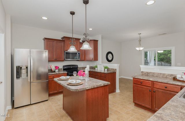 a kitchen with stainless steel appliances kitchen island granite countertop a sink refrigerator and microwave