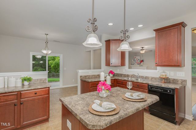 a kitchen with kitchen island granite countertop a sink a stove and a wooden cabinets
