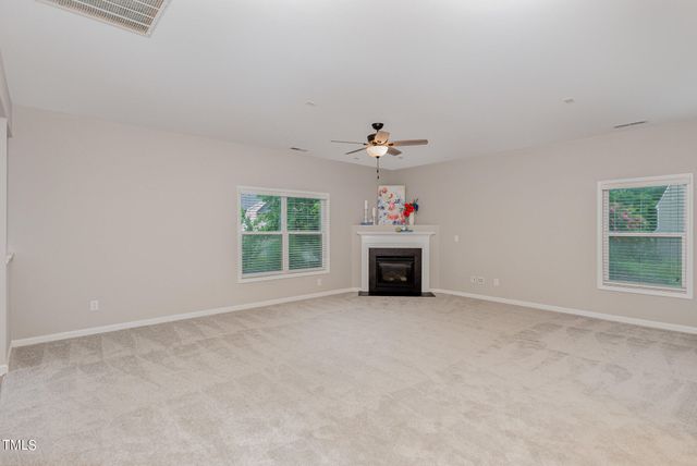 an empty room with windows and fireplace