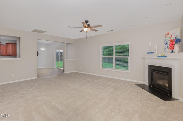 a view of livingroom with a fireplace ceiling fan and windows