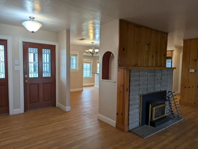 a view of an empty room with wooden floor and a fireplace