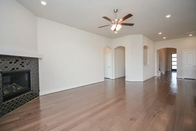 a view of an empty room with wooden floor and a fireplace