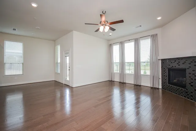 a view of an empty room with wooden floor fireplace and a window