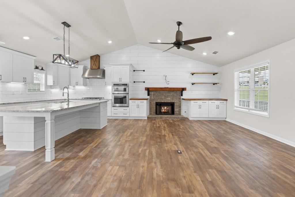 1214 Roxey Maxey Road Southwest Winder, GA 30680 - Photo 13 of 35 a open kitchen with kitchen island a stove a sink dishwasher and a fireplace with wooden floor
