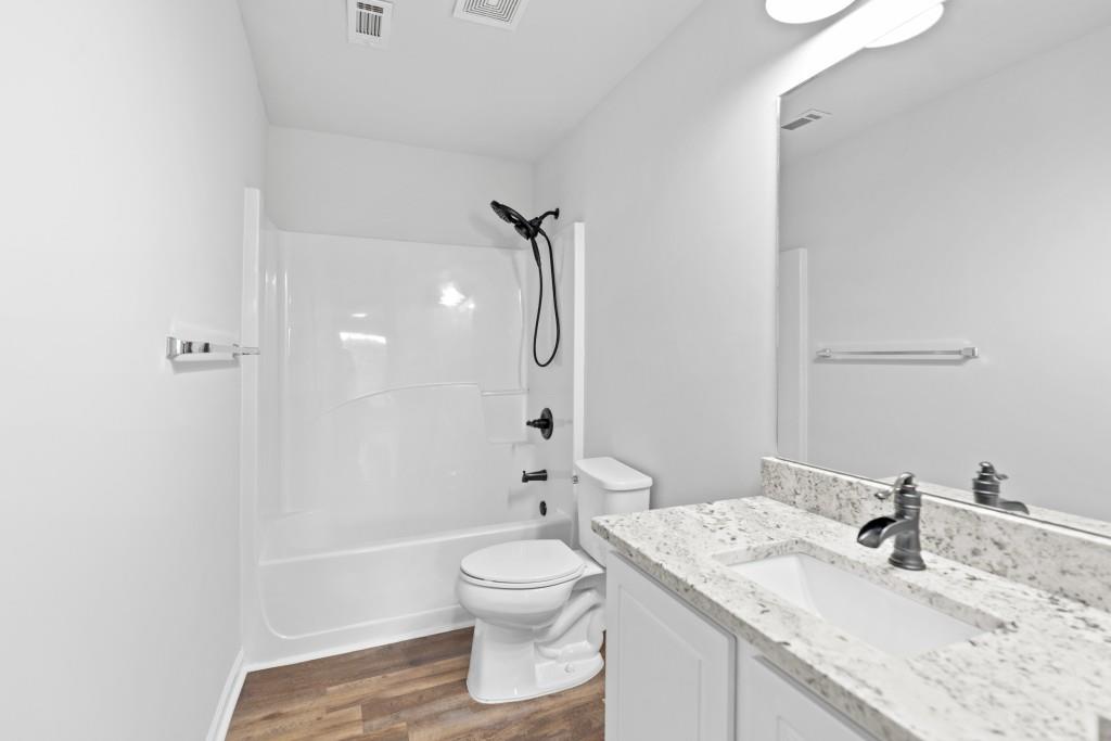 1214 Roxey Maxey Road Southwest Winder, GA 30680 - Photo 29 of 35 a bathroom with a granite countertop sink toilet a shower and a mirror