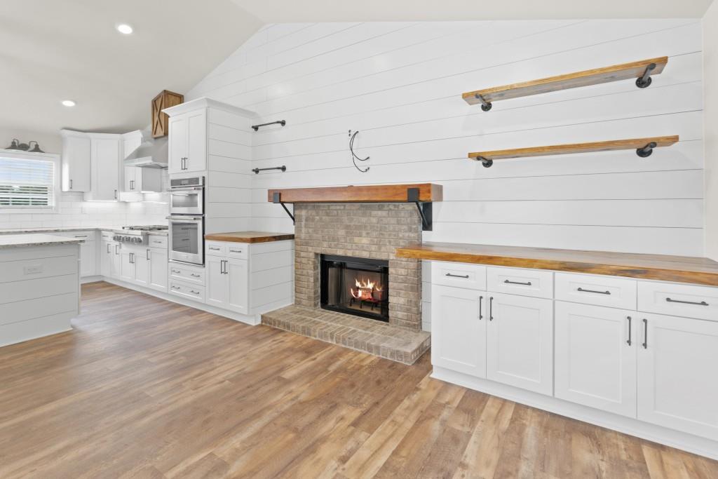 1214 Roxey Maxey Road Southwest Winder, GA 30680 - Photo 6 of 35 a open kitchen with granite countertop a fireplace cabinets and a wooden floor
