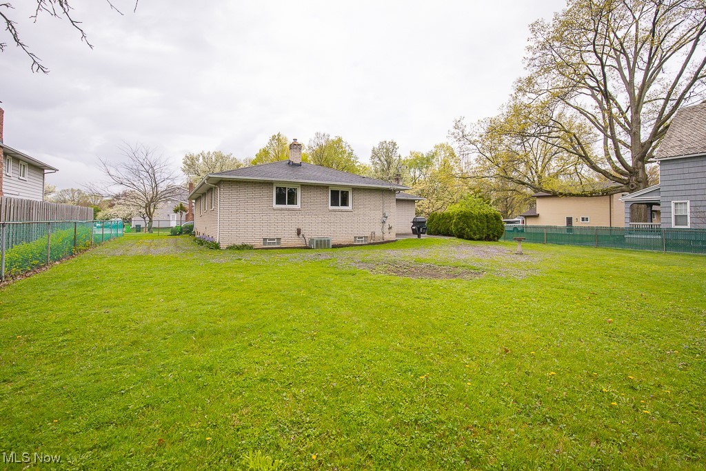 4569 McFarland Road Cleveland, OH 44121 - Photo 28 of 29 Rear view of house with a chimney, a lawn, fence, central AC, and brick siding