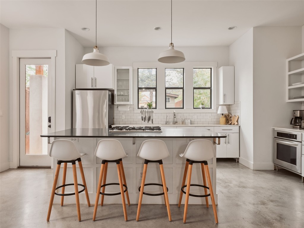 2002 East 13th Street, Unit A Austin, TX 78702 - Photo 15 of 37 Kitchen featuring white cabinets, a kitchen bar, glass insert cabinets, a kitchen island, and pendant lighting