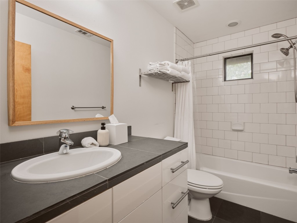 2002 East 13th Street, Unit A Austin, TX 78702 - Photo 25 of 37 Bathroom featuring shower / bath combo, vanity, and dark tile patterned floors