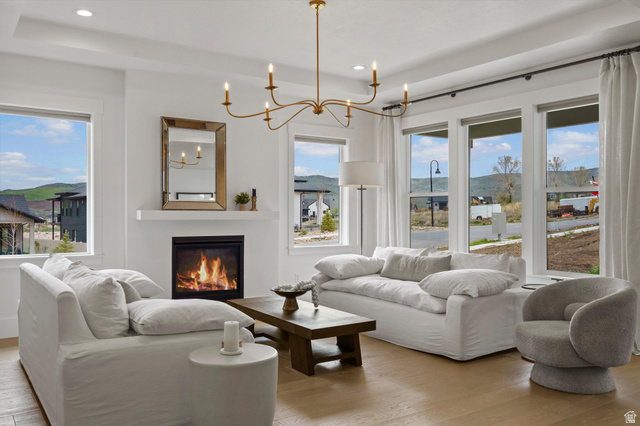 3349 Oxford Loop Morgan, UT 84050 - Photo 1 of 47 Living room with light wood-style flooring, hanging lights, a glass covered fireplace, and a raised ceiling