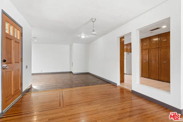 a view of empty room with wooden floor and entryway