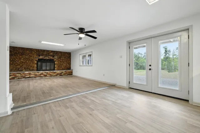 a view of an empty room with wooden floor fireplace and a window