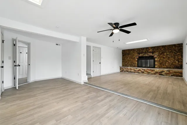 a view of an empty room with wooden floor and a fireplace